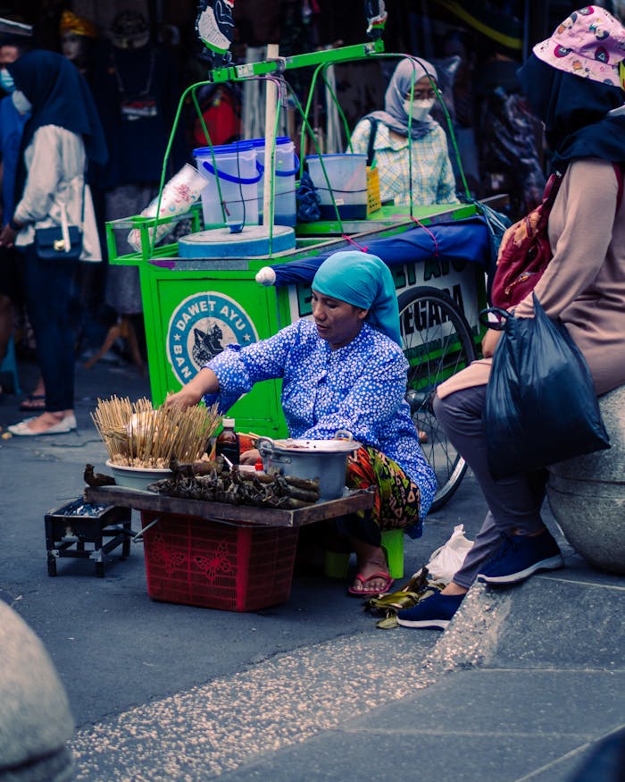gallery-6 A woman street vendor selling traditional snacks on a vibrant street in Yogyakarta, Indonesia.
