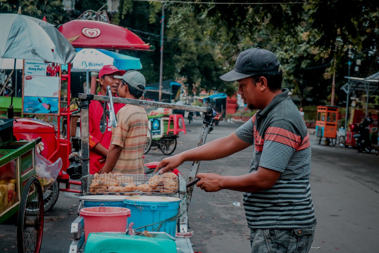 gallery-2 Street vendors in Indonesia preparing food in a bustling urban setting.