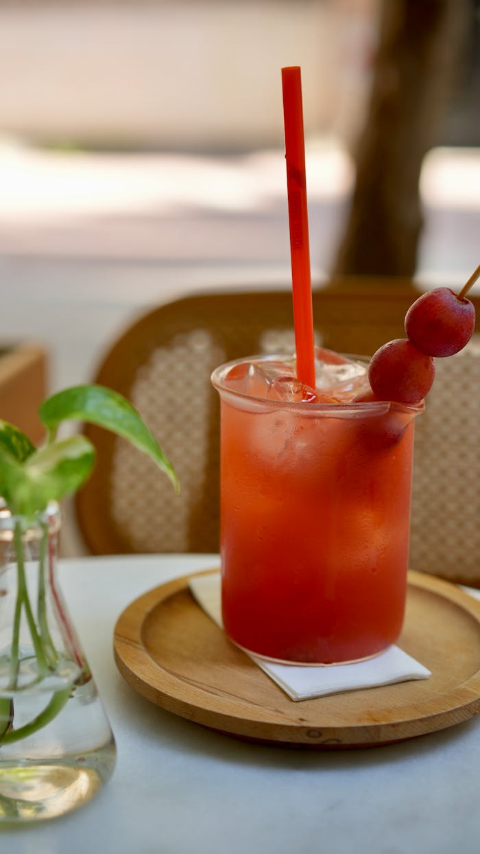 A crisp red berry drink with ice, garnished with grapes, set on a table in İstanbul café.