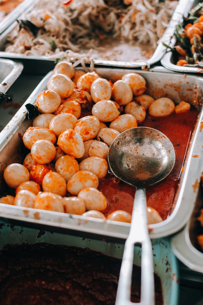 hero-img-02 Close-up of spicy quail eggs in a metal tray with a ladle. Perfect for food and cuisine stock photos.